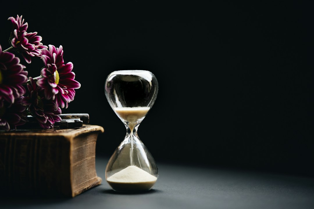 Clessidra con fiori rosa accanto, il valore del tempo